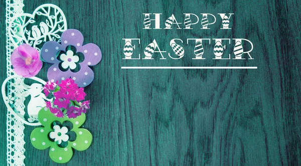 Easter card, on a background of blue wood with flowers and decoration.