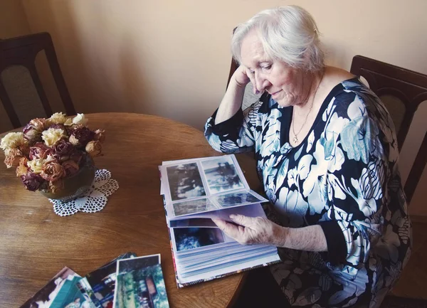 Old woman is watching an album with old photos.