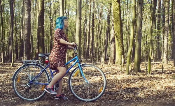 ドレスを着た少女は森の中を自転車に乗る — ストック写真