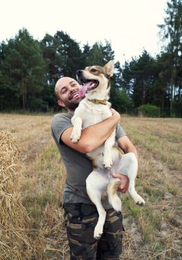 Mutlu çocuk köpeğini kollarına tutar..