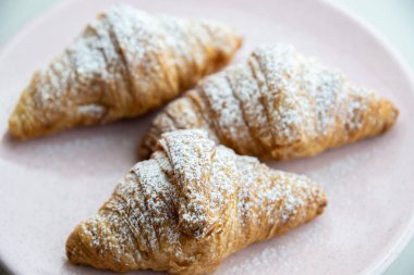 Taze pişmiş kruvasanlar şeker bir plaka üzerinde