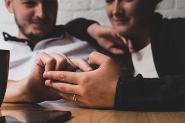 Adam el bir el okşadı. Mutlu bir adam ve kız arka planı görülebilir. Önce onları bir tablo cep telefonu üzerinde yatıyor. Fotoğraf renkli.
