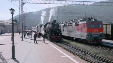 Slyudyanka, Irkutsk region, Rusya Federasyonu - 18 Ağustos 2018: eski Turizm lokomotif maliyeti tren istasyonunda. Bir borudan sigaran yoktur ve Tekerlekli çiftler altından. Turistler peron göre gidin ve fotoğraflandı.