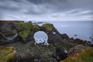 Ünlü Arnastapi İzlanda manzara sahne uzun pozlama fotoğraf olarak bulutlu sabah rock ve kayalıklarla kemer.