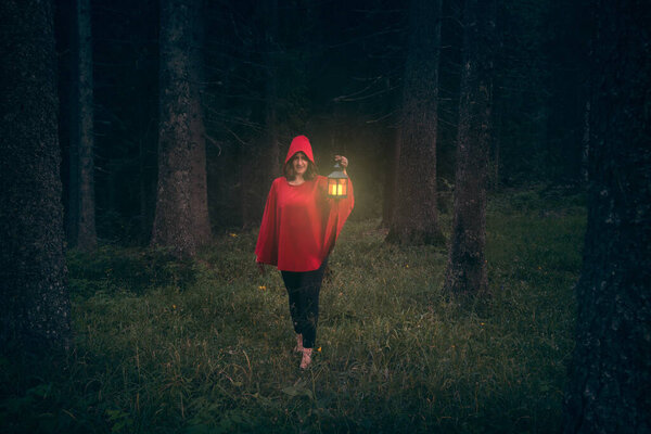 Recreating Little Red Riding Hood fairy tale as woman walking alone and lost in forest.