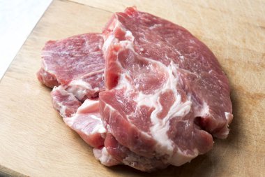 bir kesme tahtası üzerinde iki domuz eti biftek