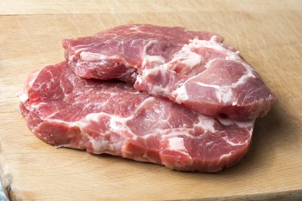 bir kesme tahtası üzerinde iki domuz eti biftek