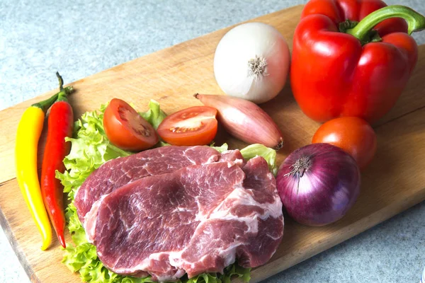 Domuz eti boyun eti biftek marul, turp, domates, kırmızı biber, sarı biber, yeşil kırmızı biber, sarı biber, kırmızı biber, kara biber ve arka plan üzerinde üzerinde. Yatay. Kırmızı soğan, arpacık. Mermer et