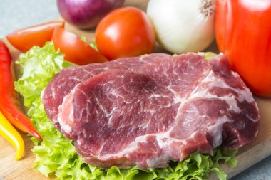 Domuz eti boyun eti biftek marul, turp, domates, kırmızı biber, sarı biber, yeşil kırmızı biber, sarı biber, kırmızı biber, kara biber ve arka plan üzerinde üzerinde. Yatay. Kırmızı soğan, arpacık. Mermer et