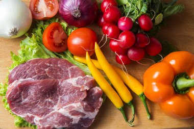 Domuz eti boyun eti biftek marul, turp, domates, kırmızı biber, sarı biber, yeşil kırmızı biber, sarı biber, kırmızı biber, kara biber ve arka plan üzerinde üzerinde. Yatay. Kırmızı soğan, arpacık. Mermer et
