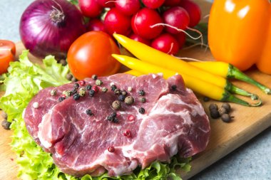 Domuz eti boyun eti biftek marul, turp, domates, kırmızı biber, sarı biber, yeşil kırmızı biber, sarı biber, kırmızı biber, kara biber ve arka plan üzerinde üzerinde. Yatay. Kırmızı soğan, arpacık. Mermer et