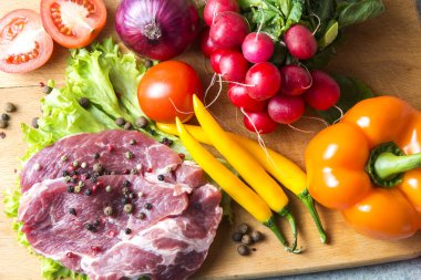 Domuz eti boyun eti biftek marul, turp, domates, kırmızı biber, sarı biber, yeşil kırmızı biber, sarı biber, kırmızı biber, kara biber ve arka plan üzerinde üzerinde. Yatay. Kırmızı soğan, arpacık. Mermer et