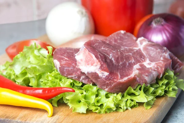 Domuz eti boyun eti biftek marul, turp, domates, kırmızı biber, sarı biber, yeşil kırmızı biber, sarı biber, kırmızı biber, kara biber ve arka plan üzerinde üzerinde. Yatay. Kırmızı soğan, arpacık. Mermer et