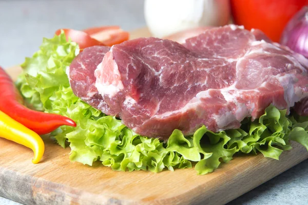 Domuz eti boyun eti biftek marul, turp, domates, kırmızı biber, sarı biber, yeşil kırmızı biber, sarı biber, kırmızı biber, kara biber ve arka plan üzerinde üzerinde. Yatay. Kırmızı soğan, arpacık. Mermer et