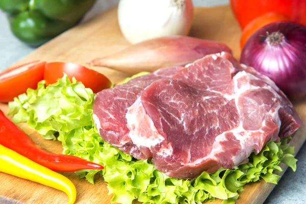 Domuz eti boyun eti biftek marul, turp, domates, kırmızı biber, sarı biber, yeşil kırmızı biber, sarı biber, kırmızı biber, kara biber ve arka plan üzerinde üzerinde. Yatay. Kırmızı soğan, arpacık. Mermer et