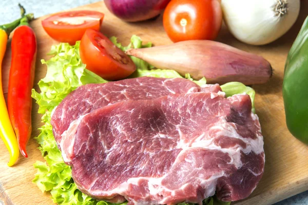 Domuz eti boyun eti biftek marul, turp, domates, kırmızı biber, sarı biber, yeşil kırmızı biber, sarı biber, kırmızı biber, kara biber ve arka plan üzerinde üzerinde. Yatay. Kırmızı soğan, arpacık. Mermer et