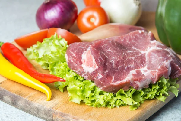 Domuz eti boyun eti biftek marul, turp, domates, kırmızı biber, sarı biber, yeşil kırmızı biber, sarı biber, kırmızı biber, kara biber ve arka plan üzerinde üzerinde. Yatay. Kırmızı soğan, arpacık. Mermer et