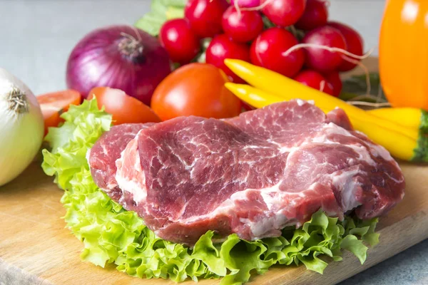 Domuz eti boyun eti biftek marul, turp, domates, kırmızı biber, sarı biber, yeşil kırmızı biber, sarı biber, kırmızı biber, kara biber ve arka plan üzerinde üzerinde. Yatay. Kırmızı soğan, arpacık. Mermer et