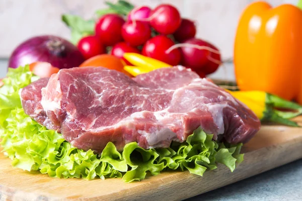 Domuz eti boyun eti biftek marul, turp, domates, kırmızı biber, sarı biber, yeşil kırmızı biber, sarı biber, kırmızı biber, kara biber ve arka plan üzerinde üzerinde. Yatay. Kırmızı soğan, arpacık. Mermer et