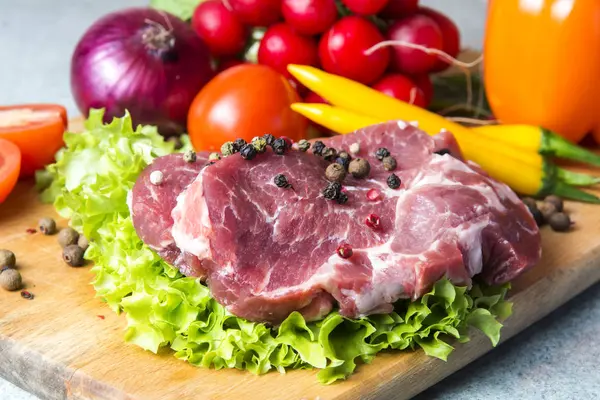 Domuz eti boyun eti biftek marul, turp, domates, kırmızı biber, sarı biber, yeşil kırmızı biber, sarı biber, kırmızı biber, kara biber ve arka plan üzerinde üzerinde. Yatay. Kırmızı soğan, arpacık. Mermer et