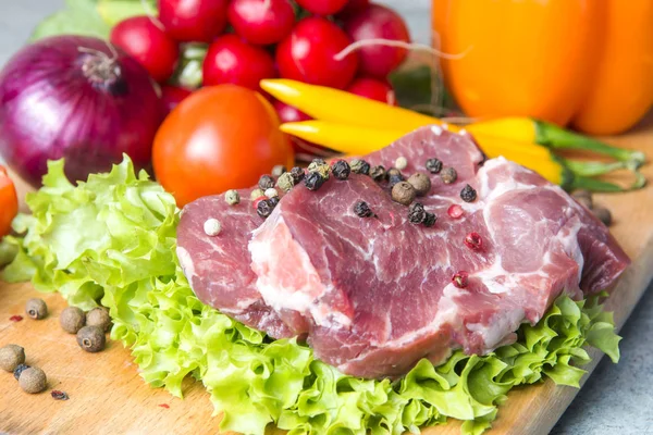 Domuz eti boyun eti biftek marul, turp, domates, kırmızı biber, sarı biber, yeşil kırmızı biber, sarı biber, kırmızı biber, kara biber ve arka plan üzerinde üzerinde. Yatay. Kırmızı soğan, arpacık. Mermer et