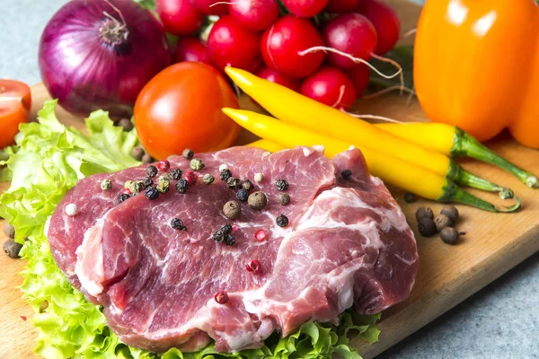 Domuz eti boyun eti biftek marul, turp, domates, kırmızı biber, sarı biber, yeşil kırmızı biber, sarı biber, kırmızı biber, kara biber ve arka plan üzerinde üzerinde. Yatay. Kırmızı soğan, arpacık. Mermer et