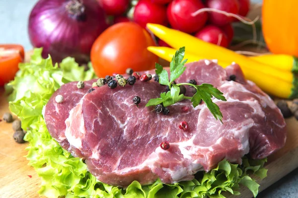 Domuz eti boyun eti biftek marul, turp, domates, kırmızı biber, sarı biber, yeşil kırmızı biber, sarı biber, kırmızı biber, kara biber ve arka plan üzerinde üzerinde. Yatay. Kırmızı soğan, arpacık. Mermer et