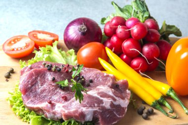 Domuz eti boyun eti biftek marul, turp, domates, kırmızı biber, sarı biber, yeşil kırmızı biber, sarı biber, kırmızı biber, kara biber ve arka plan üzerinde üzerinde. Yatay. Kırmızı soğan, arpacık. Mermer et