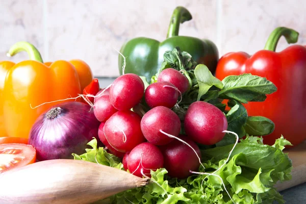 sebze karışımı mutfak. Turp, domates, kırmızı biber, yeşil kırmızı biber, sarı kırmızı biber, kırmızı sıcak biber biber, sarı sıcak biber, kırmızı soğan, marul üzerinde kesme tahtası.
