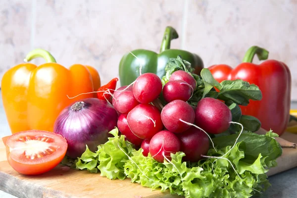 sebze karışımı mutfak. Turp, domates, kırmızı biber, yeşil kırmızı biber, sarı kırmızı biber, kırmızı sıcak biber biber, sarı sıcak biber, kırmızı soğan, marul üzerinde kesme tahtası.