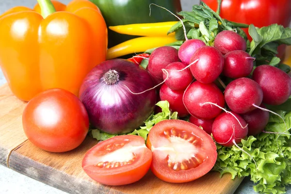 sebze karışımı mutfak. Turp, domates, kırmızı biber, yeşil kırmızı biber, sarı kırmızı biber, kırmızı sıcak biber biber, sarı sıcak biber, kırmızı soğan, marul üzerinde kesme tahtası.