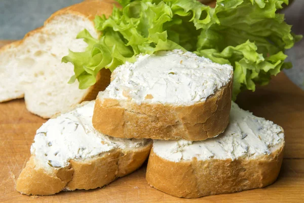 Mini baget sandviç kesme tahtası üzerinde krem peynirli