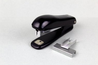 Hafif bir arka plan üzerinde siyah plastik ve ataşyapılmış zımba.