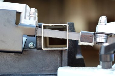 Bir ağaç altında dekore edilmiş bir kare metal boru kesme, bir Band testere.