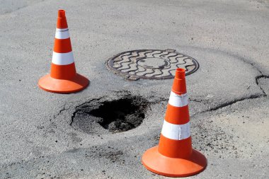 İki sinyal konisi ile çitle çevrili asfalt çukur. Güvenlik hareketi.