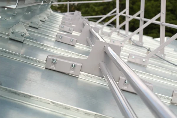 Elements of the roof fence fastening, steel clamps installed on the galvanized roof.