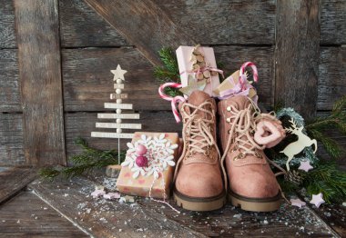 Ahşap zemin üzerinde Noel hediyeleri olan kırsal çizmeler.