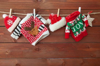Little knitted christmas pullovers on a wooden background clipart