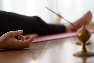 Yoga yapan bir kadın, yoga pozisyonunda yalan söyleyen Nidra pozu, Shavasana 'da egzersiz, egzersiz, iş, antrenmandan sonra dinlenme, kadın eli. Sağlıklı yaşam tarzı kavramı