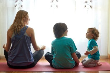 Anne ve çocuklar evdeki oturma odasında meditasyon yapıyorlar.