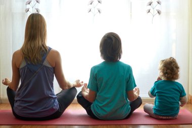 Anne ve çocuklar evdeki oturma odasında meditasyon yapıyorlar.