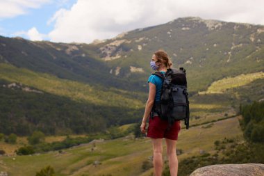 Kadın yalnız başına yürüyüş yapıyor, yüzünde koruyucu maskesiyle, yaşam tarzıyla.