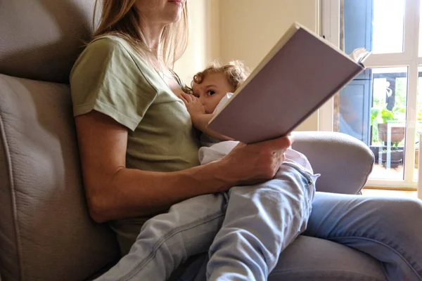 Mother Breastfeeds Her Child While Reading Relaxed Book — Stock Photo, Image