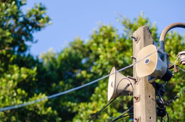 Hoparlör boynuz elektrik kutup mavi gökyüzü ve yeşil ağaç karşı