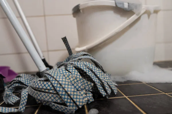Beyaz ve siyah kiremit arka plan, kova ile Süpürge ve paspas. Banyo temizliği. Arka plan için fotoğraf, metin için bir yer var.