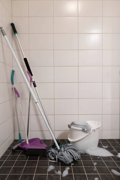 Beyaz ve siyah kiremit arka plan, kova ile Süpürge ve paspas. Banyo temizliği. Arka plan için fotoğraf, metin için bir yer var.
