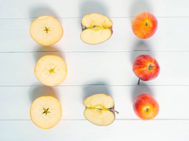 Kırmızı elmalar ve elmalar beyaz arkaplanda ikiye ayrılır. Elmadan yapılmış çerçeve sonbahar kompozisyonu. Desen.