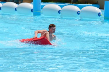 Genç adam bir slayt içinde bir su parkı binmek