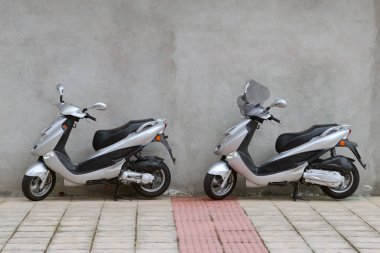Park etmiş iki scooter duvara yakın: