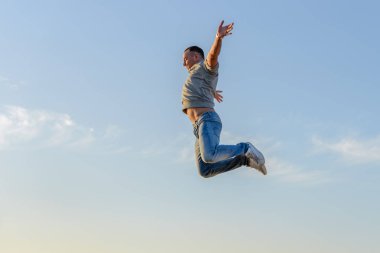 Genç adam bir atlama mavi gökyüzü karşı